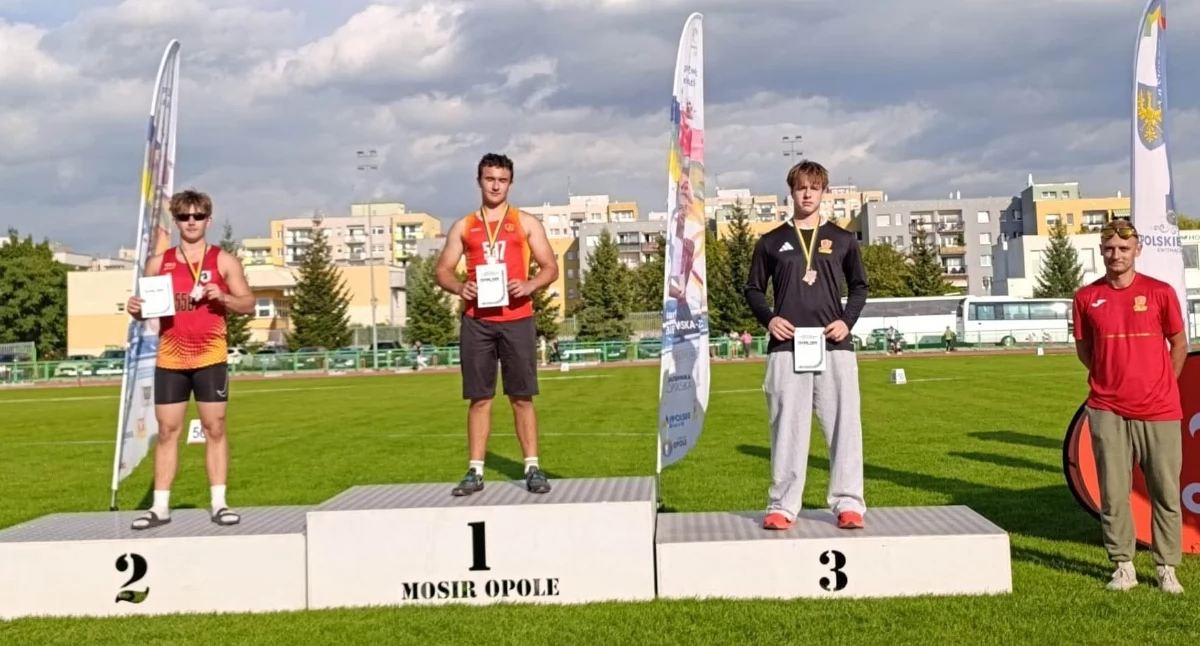Medalowe podium dla Juvenii Głuchołazy. Najlepsi dyskobole. Od lewej: Szymon Dżugała, Wiktor Łępski i Oskar Olchawa. Obok podium twórca potęgi głuchołaskiej lekkoatletyki - Paweł Pieróg 